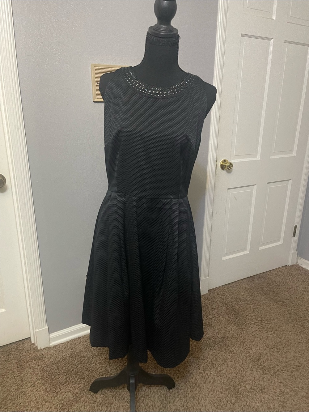 Black A-line sleeveless dress with jewel detailing around the neck